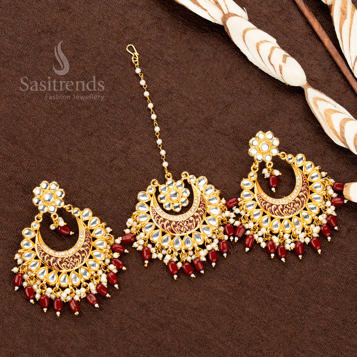 Exquisite gold plated tikka and earrings, featuring maroon handcrafted floral paintwork, intricate stone highlights, and classic bead details, offering a luxurious ethnic jewellery aesthetic - Sasitrends