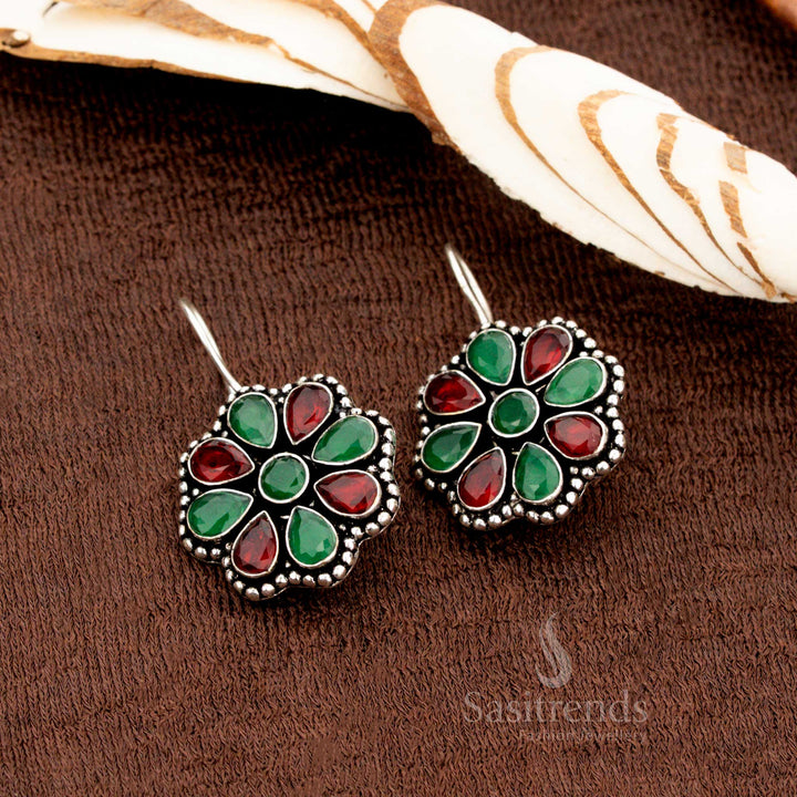 Traditional oxidised earrings crafted with ruby-green stones in a detailed floral motif and glitter finish—a striking ethnic jewellery design perfect for weddings, pujas, and festive gatherings - Sasitrends