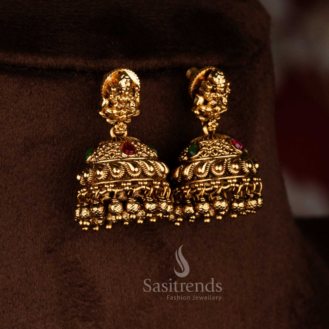 Traditional temple style matte gold ruby green AD stone Lakshmi Devi jhumka earrings with sculpted stud motif and rich layered bead detailing, high quality jewellery for saree wear- Sasitrends