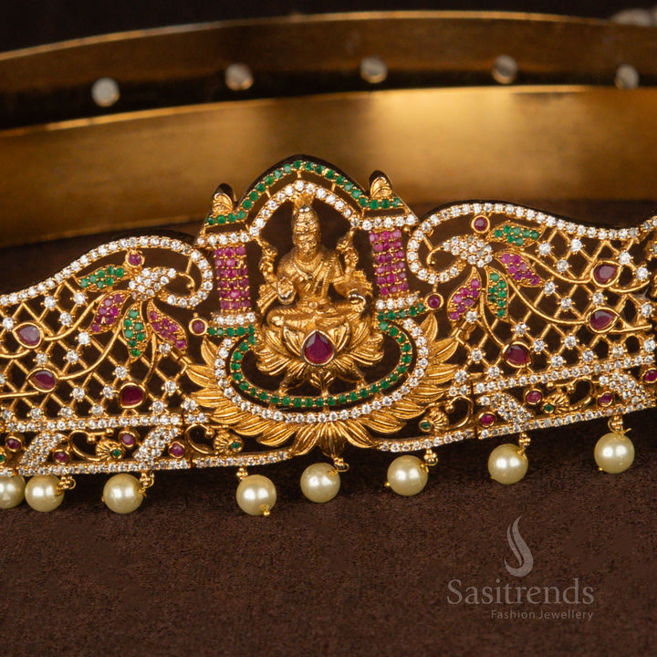 Opulent temple-style gold-plated Lakshmi hip chain with a detailed mesh pattern, adorned with sparkling ruby and green AD stones and dangling pearls, ideal for ethnic and bridal ensembles - Sasitrends