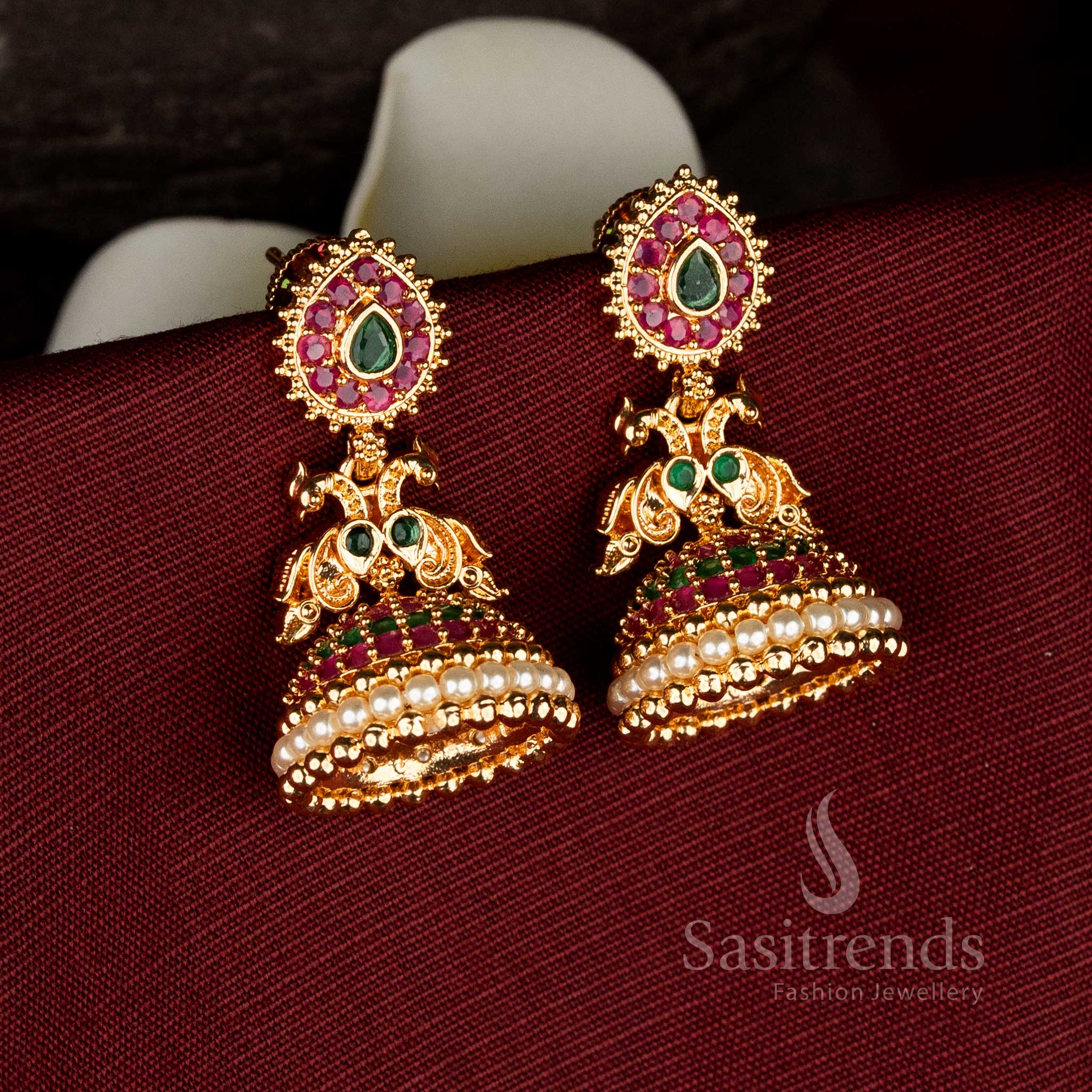 Traditional one gram micro gold plated earrings with teardrop stud design, dual peacock detailing, ruby green American diamond stone work, and pearl jhumka base