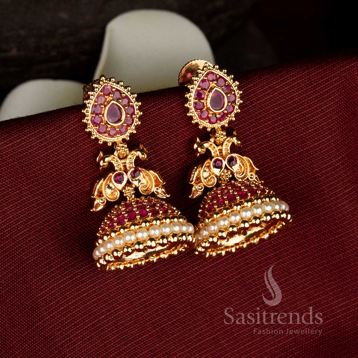 Sasitrends micro gold plated pearl ruby AD stone jhumka earrings designed with teardrop motif stud, dual peacock structure, and dome-shaped traditional craftsmanship
