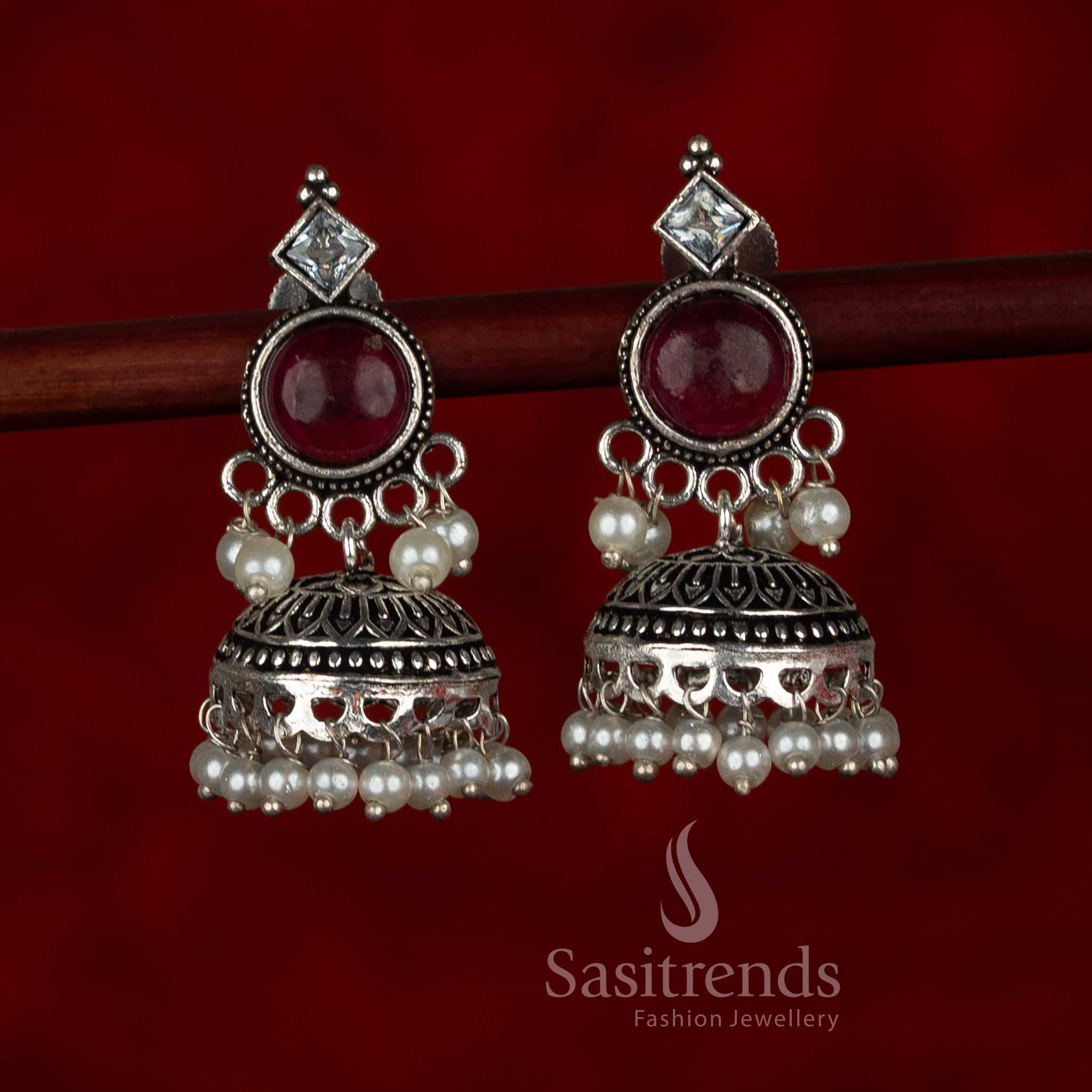 Sasitrends oxidised silver plated jhumka earrings featuring circular stud tops, layered dome structure with engraved detailing, and pearl bead hangings in a ruby and white color combination, suitable for ethnic wear, casual wear, office wear, and modern saree styling
