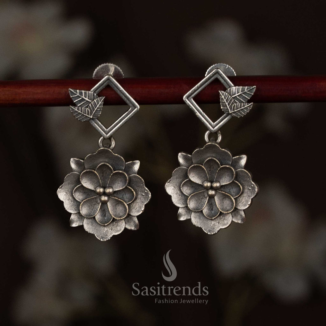 Sasitrends antique oxidised 92.5 silver plated earrings featuring a geometric diamond-shaped top connected to a layered floral drop motif with sculpted petal detailing, heritage-inspired silver finish, and elegant ethnic design
