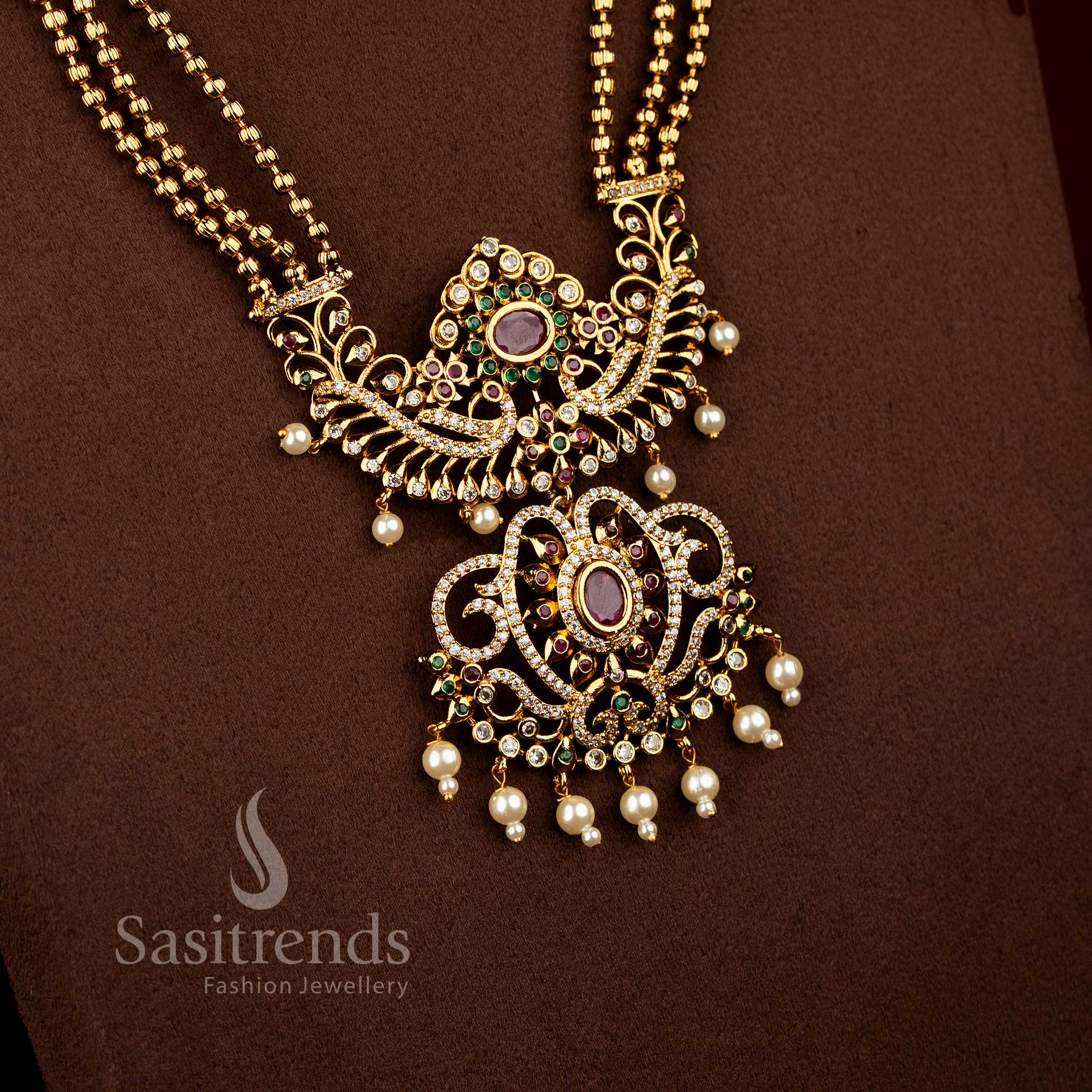 Sasitrends bridal temple matte gold plated multi AD stone long necklace set featuring triple layered chain design with ornate peacock floral centre pendant