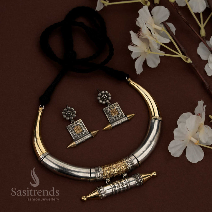 Sasitrends 92.5 dual tone silver oxidised husli necklace jewellery set featuring a bold curved crescent tubular design with smooth polished upper sections, an engraved cylindrical barrel motif at the center with repetitive geometric patterns, pointed decorative end caps, traditional thread fastening, and matching earrings designed with floral stud tops and square engraved panel drops for ethnic heritage styling.