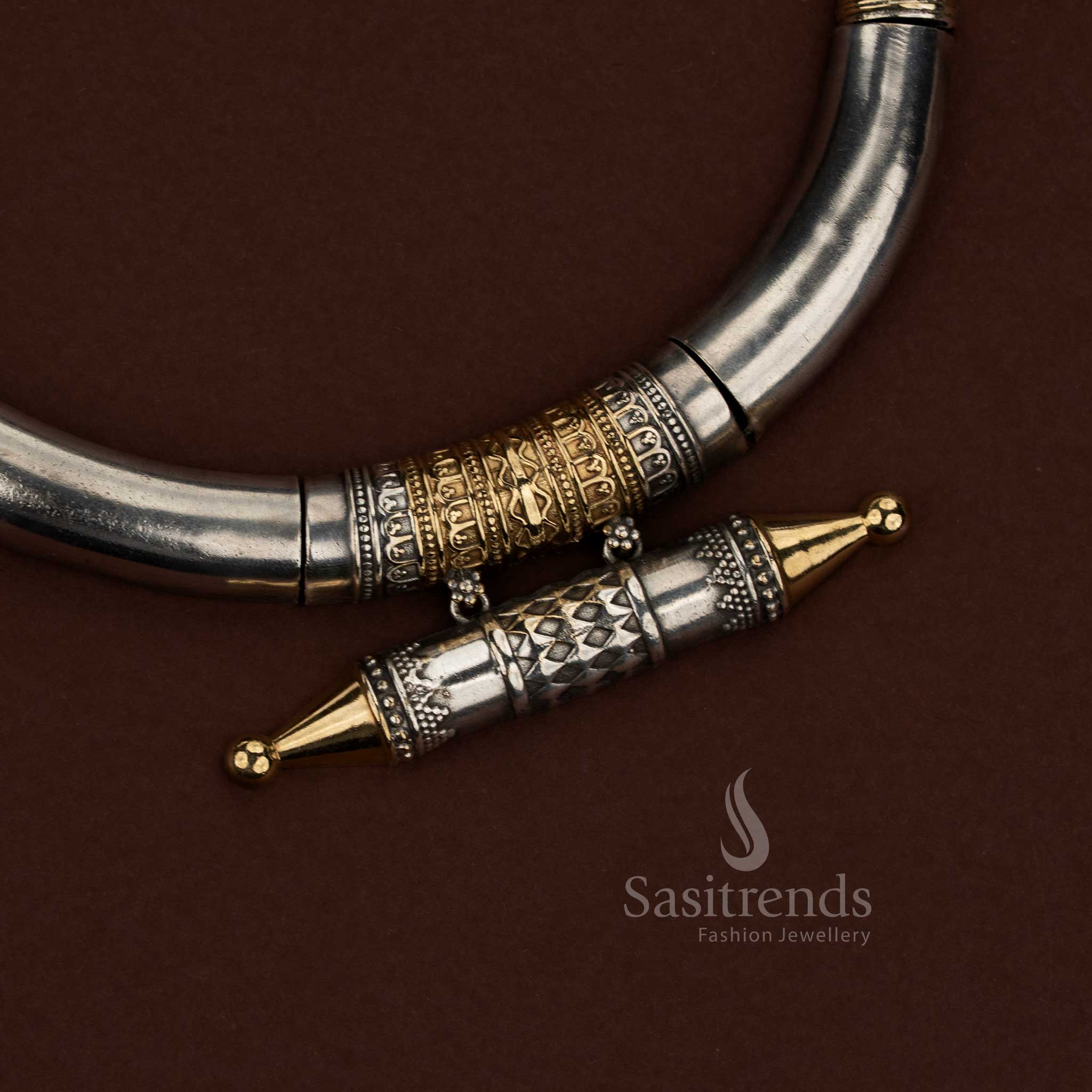 Sasitrends oxidised silver husli jewellery set designed with a strong sculpted crescent silhouette, dual tone metal contrast, detailed engraved barrel centerpiece, geometric surface textures along the necklace body, and coordinated earrings combining floral motifs with structured square panel design suitable for festive and cultural wear.