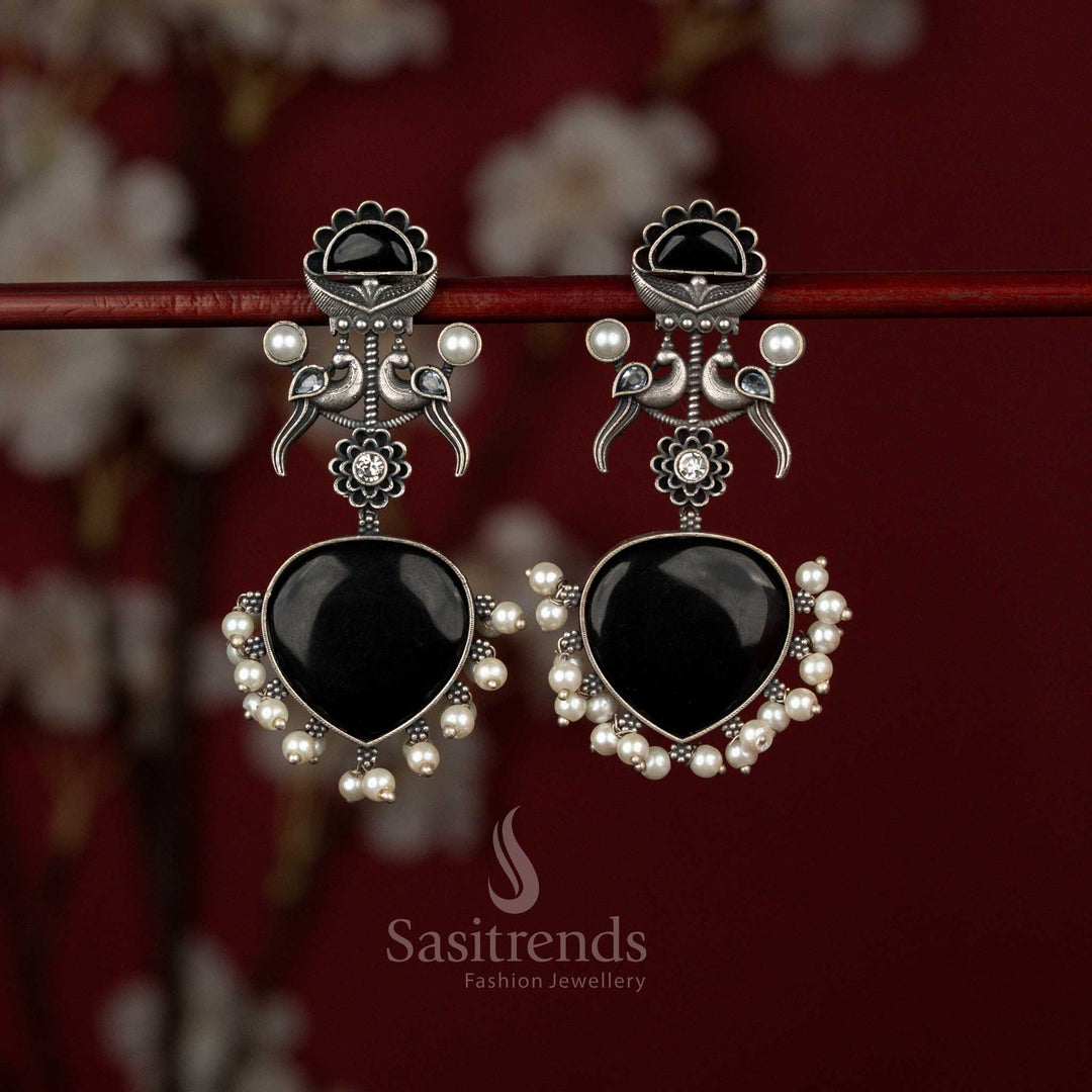 Antique style black oxidised German silver earrings from Sasitrends crafted with double peacock motifs forming a heart shape and finished with elegant pearl drops for ethnic wear