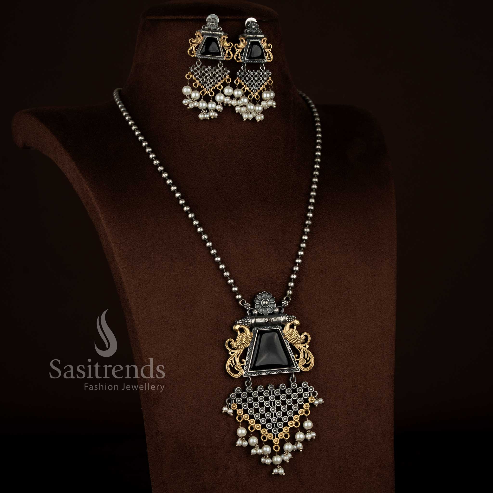 Antique oxidised silver plated floral peacock motif pendant chain necklace set from Sasitrends featuring a black Monalisa stone centerpiece, pearl detailing, rich antique finish, detailed peacock and floral carving, and matching earrings for temple and festive jewellery looks.
