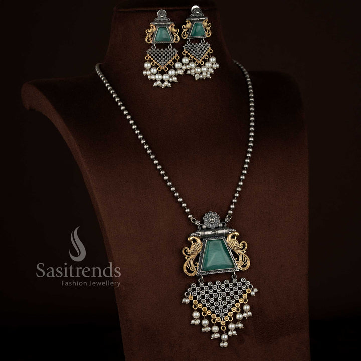 Sasitrends antique oxidised silver plated necklace set showcasing a mint Monalisa stone floral peacock motif pendant with pearl embellishments, intricate antique engraving, matching earrings reflecting the same floral peacock design, and a heritage-inspired chain.
