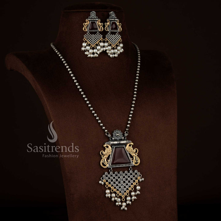 Sasitrends antique oxidised 92.5 silver plated necklace set showcasing a red Monalisa stone floral peacock motif pendant with pearl accents, engraved antique finish, matching earrings with traditional peacock design, and a coordinated oxidised chain.
