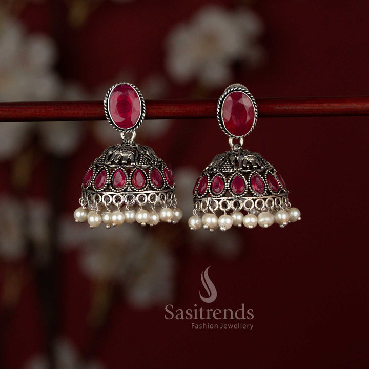 Antique style ruby oxidised German silver earrings from Sasitrends designed with a polished Monalisa oval stud, sculpted elephant centerpiece, teardrop stone accents and layered pearl jhumka hangings ideal for sarees and cultural celebrations.