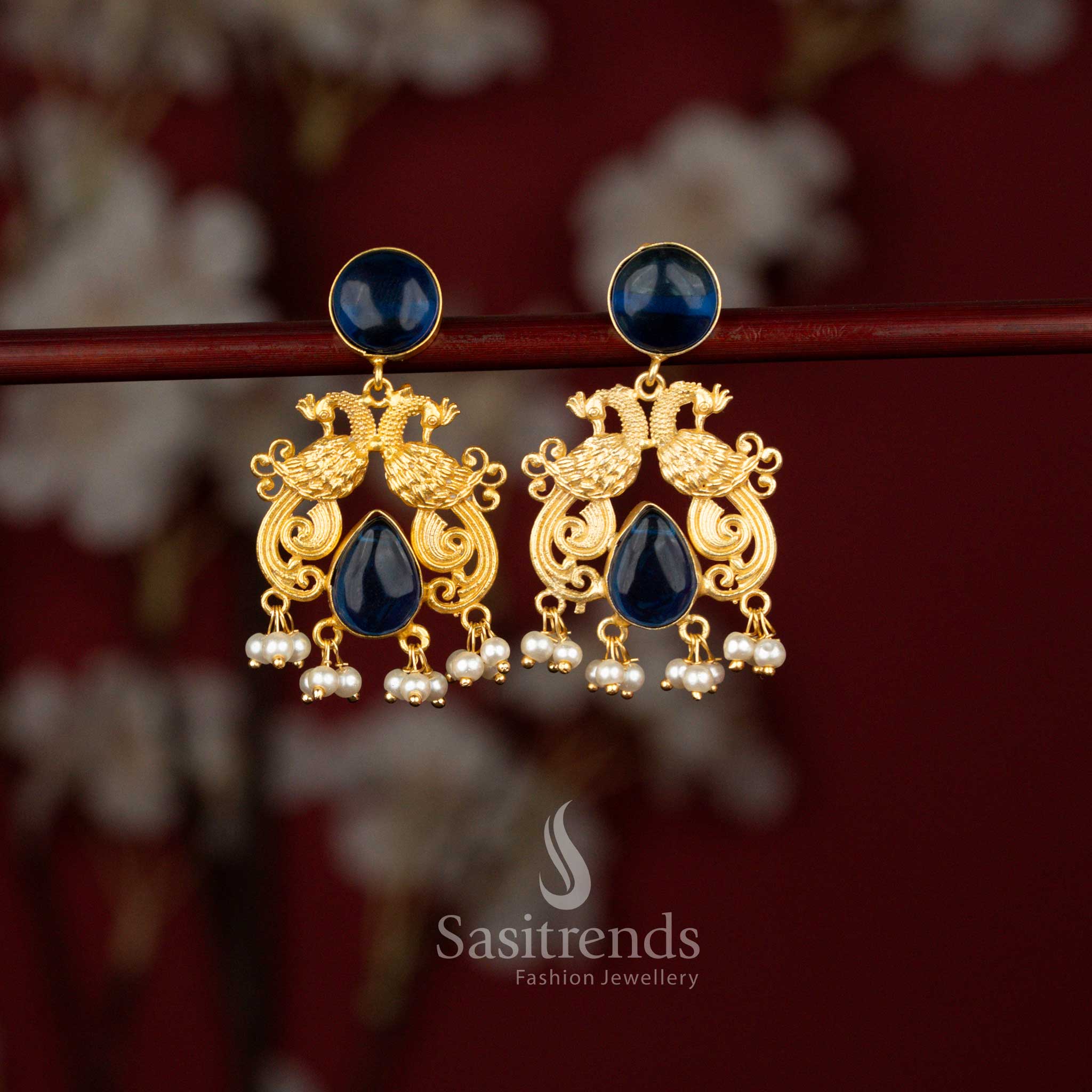 Grand blue 24K gold plated dual peacock earrings by Sasitrends showcasing intricate circular artistry, shimmering teardrop stones and layered pearl hangings ideal for temple visits and festive gatherings.