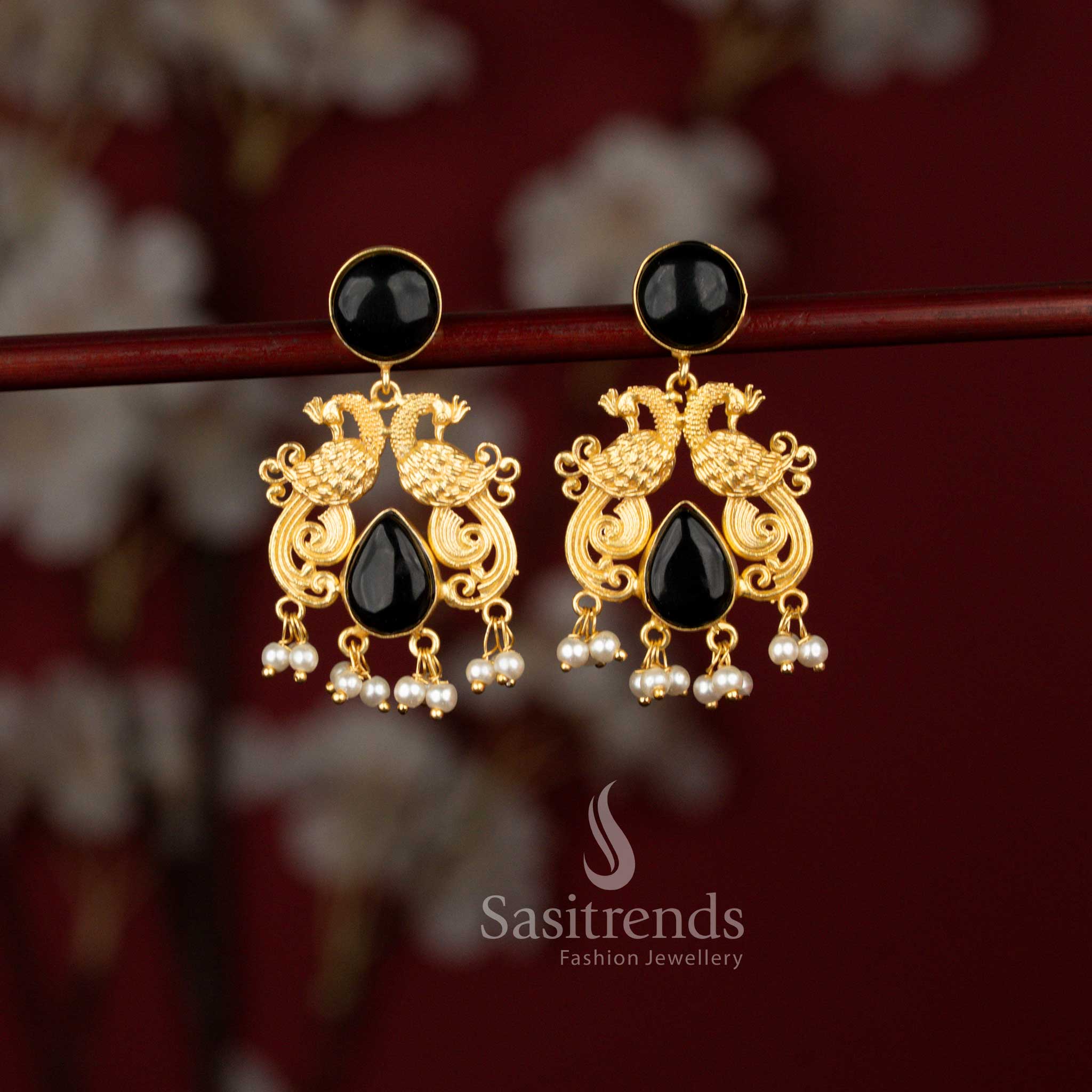Sasitrends classic 24K gold plated earrings showcasing twin peacock motifs framed in a circular pattern, highlighted with teardrop black stones and finished with pearl detailing for weddings and special occasions.
