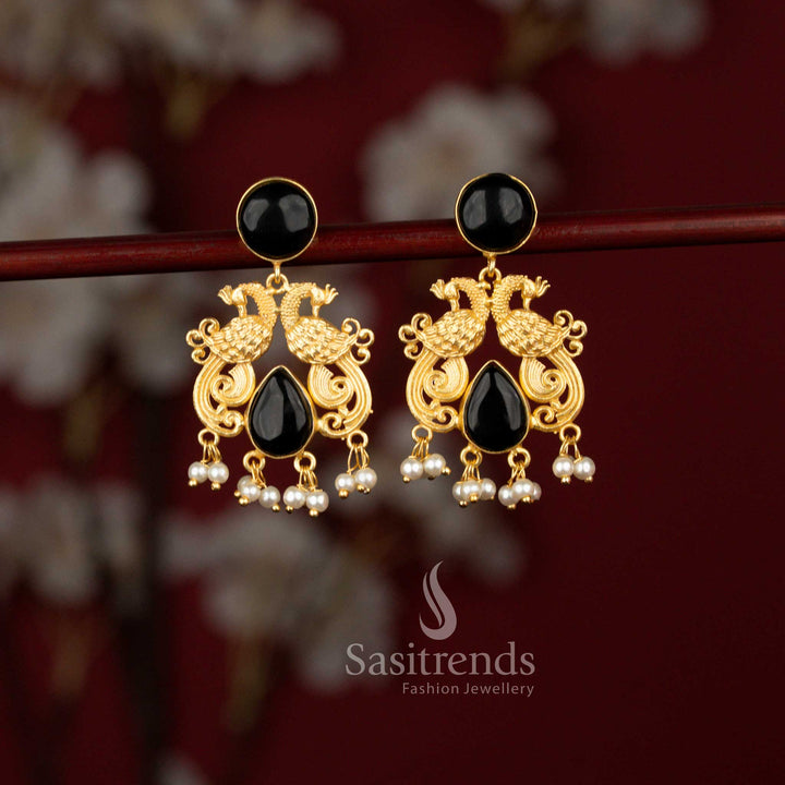 Sasitrends classic 24K gold plated earrings showcasing twin peacock motifs framed in a circular pattern, highlighted with teardrop black stones and finished with pearl detailing for weddings and special occasions.
