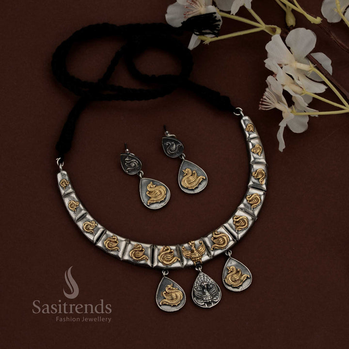 Sasitrends dual tone oxidised plated silver husli necklace set showcasing a structured segmented design with sculpted peacock motifs across each panel, oxidised surface texture with highlighted detailing, suspended teardrop danglers for depth and balance, traditional thread closure, and matching earrings reflecting the same peacock and layered design language.