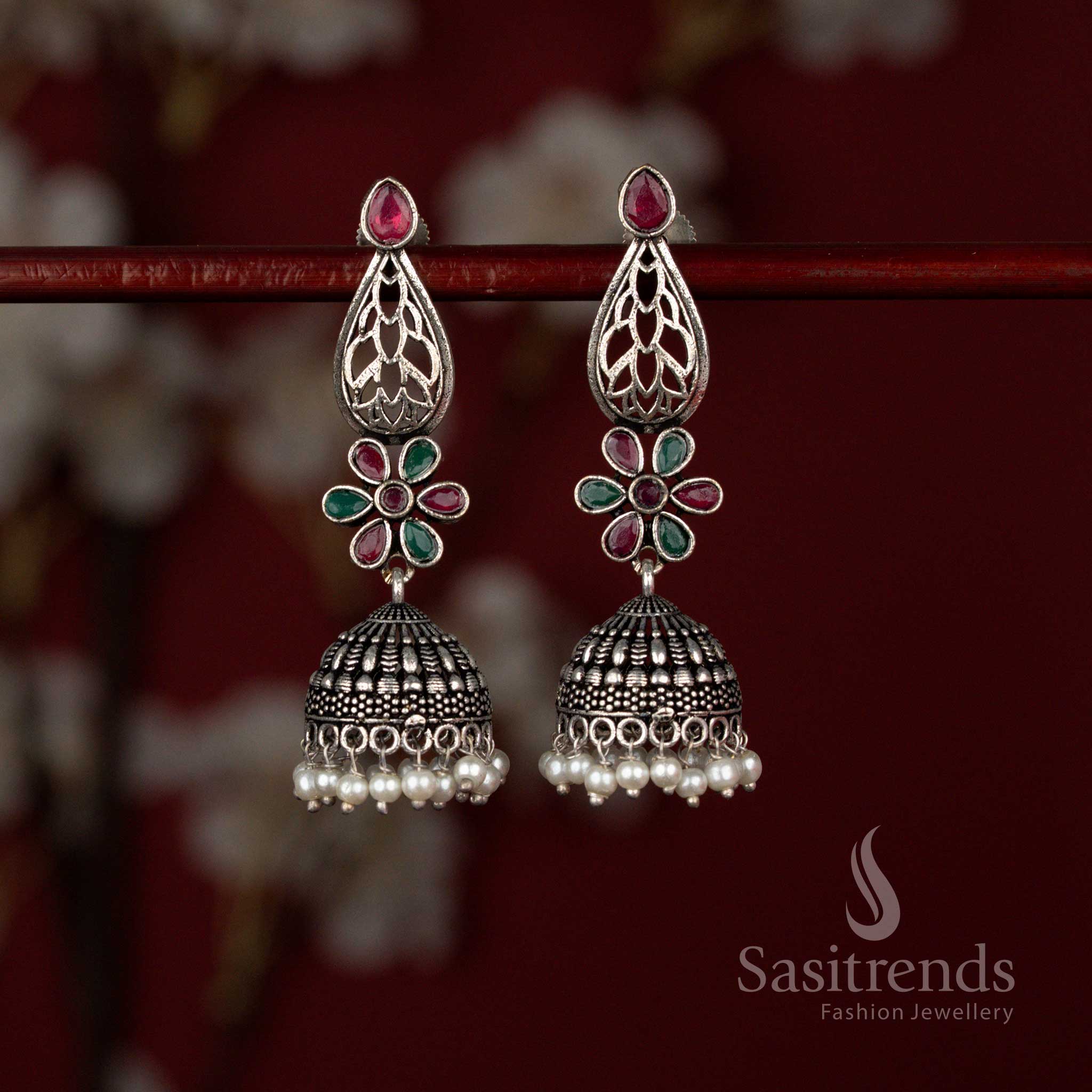 Grand oxidised German silver jhumka earrings by Sasitrends showcasing a teardrop cut ruby green Monalisa stone framed with intricate floral motifs and finished with delicate pearl drops for festive styling.