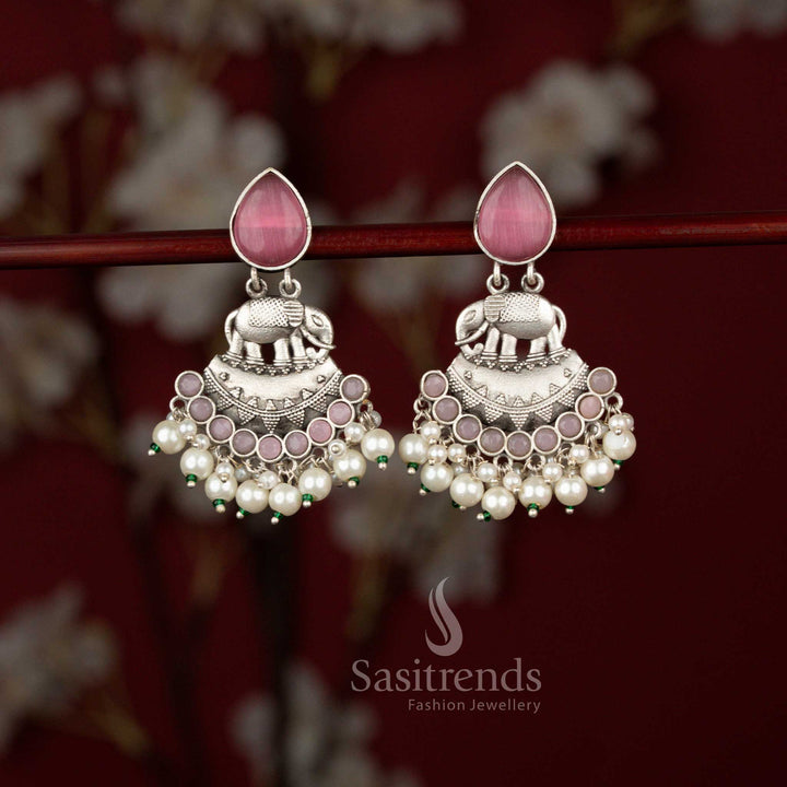 Grand Majesty pink oxidised silver earrings from Sasitrends featuring intricate elephant detailing, a bold crescent framework, shimmering teardrop stone accents and graceful pearl embellishments for festive sarees and cultural events.