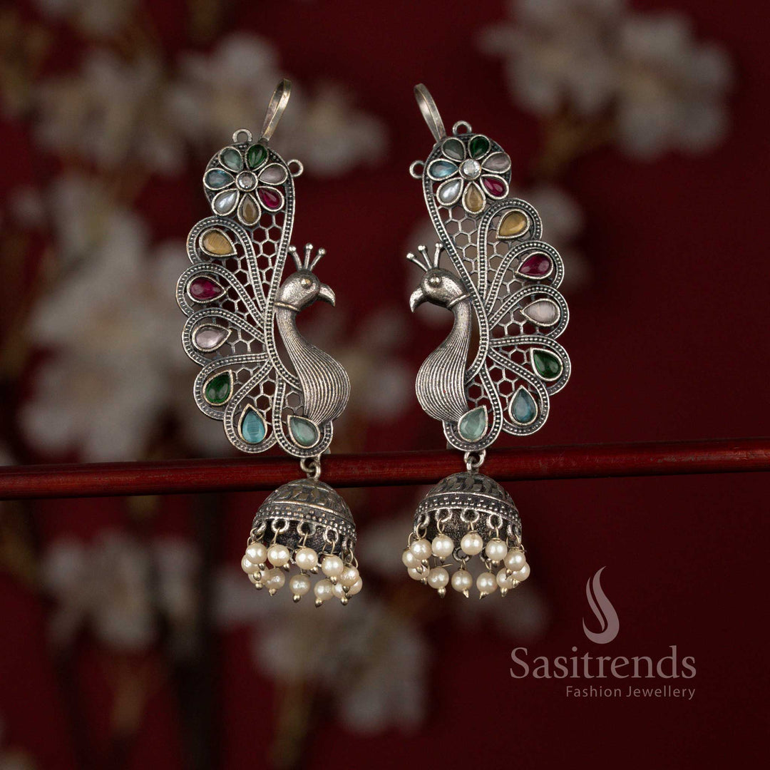 Heritage inspired 92.5 silver plated oxidised multi earrings by Sasitrends featuring a sculpted peacock motif, floral accents, teardrop stone embellishments and elegant pearl hangings for cultural celebrations.