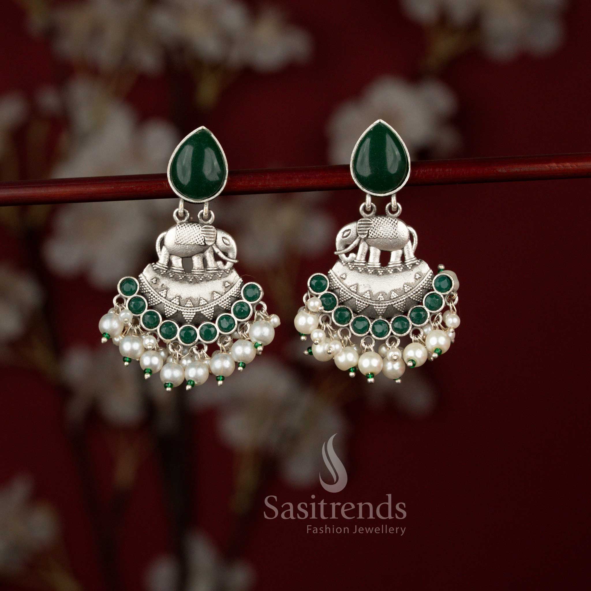 Luxury antique green oxidised silver earrings from Sasitrends designed with a symbolic elephant centerpiece, curved crescent artistry, luminous teardrop stone detailing and soft pearl drops that beautifully complement sarees and festive ensembles.