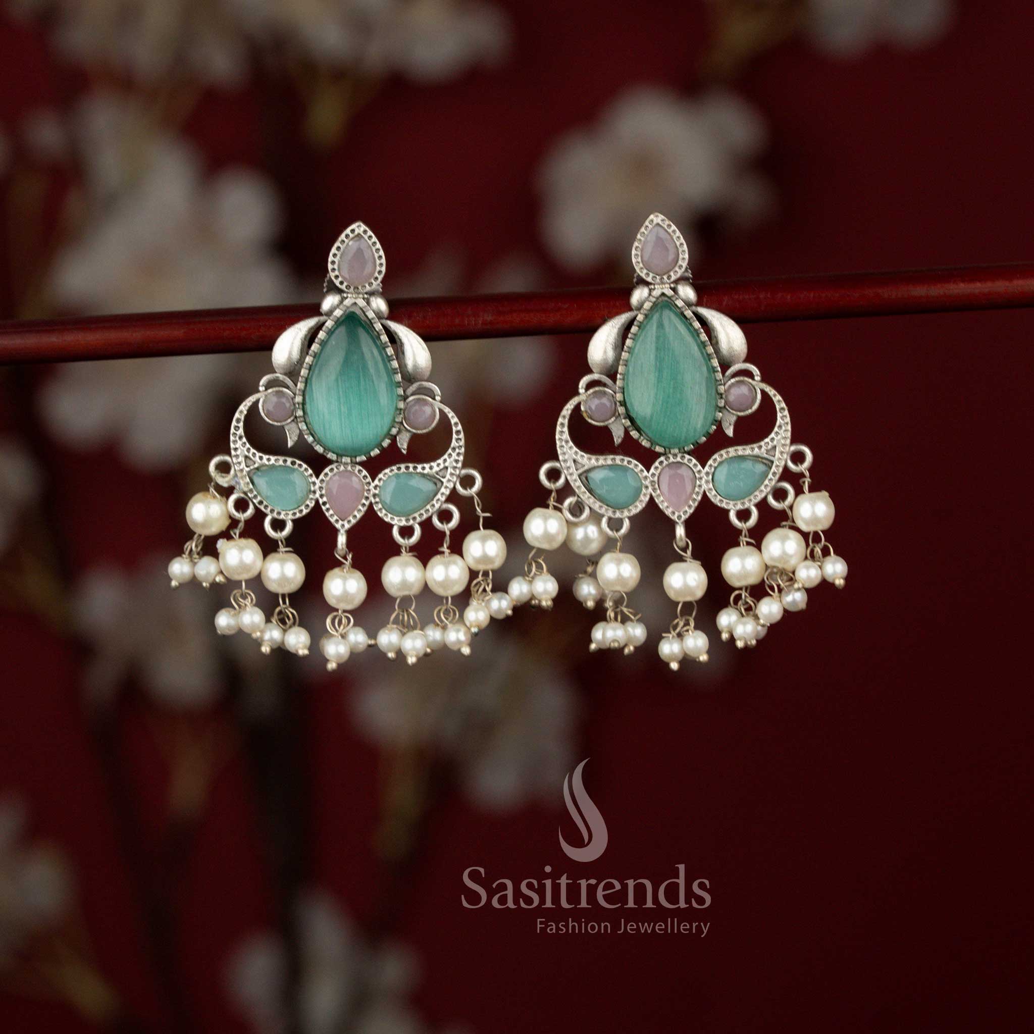 Sasitrends mint pink antique inspired Peacock Eleganza earrings crafted in oxidised silver tone with sculpted peacock detailing, luminous teardrop stones and refined pearl hangings ideal for Navaratri evenings and saree styling.
