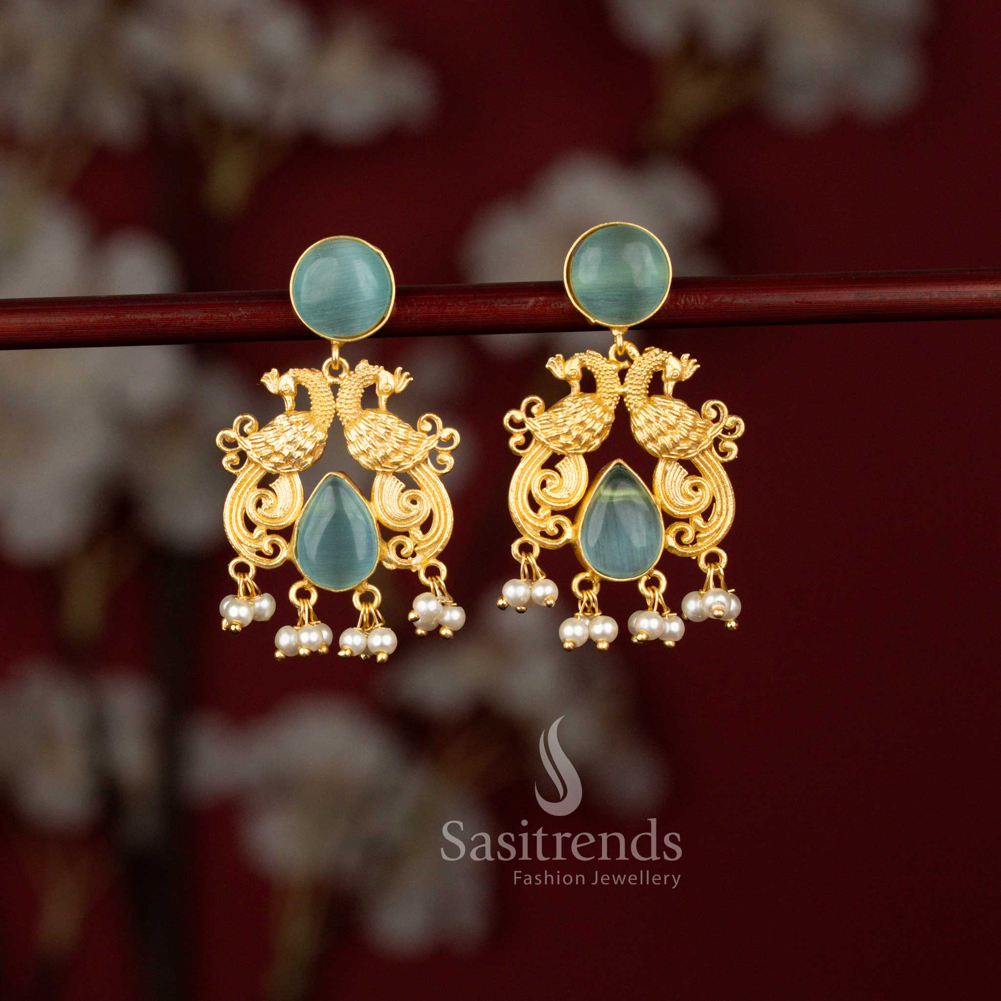 Premium ocean blue 24K gold plated dual peacock earrings from Sasitrends designed with a detailed round frame, luminous teardrop stone centerpiece and pearl embellishments for rich traditional styling.