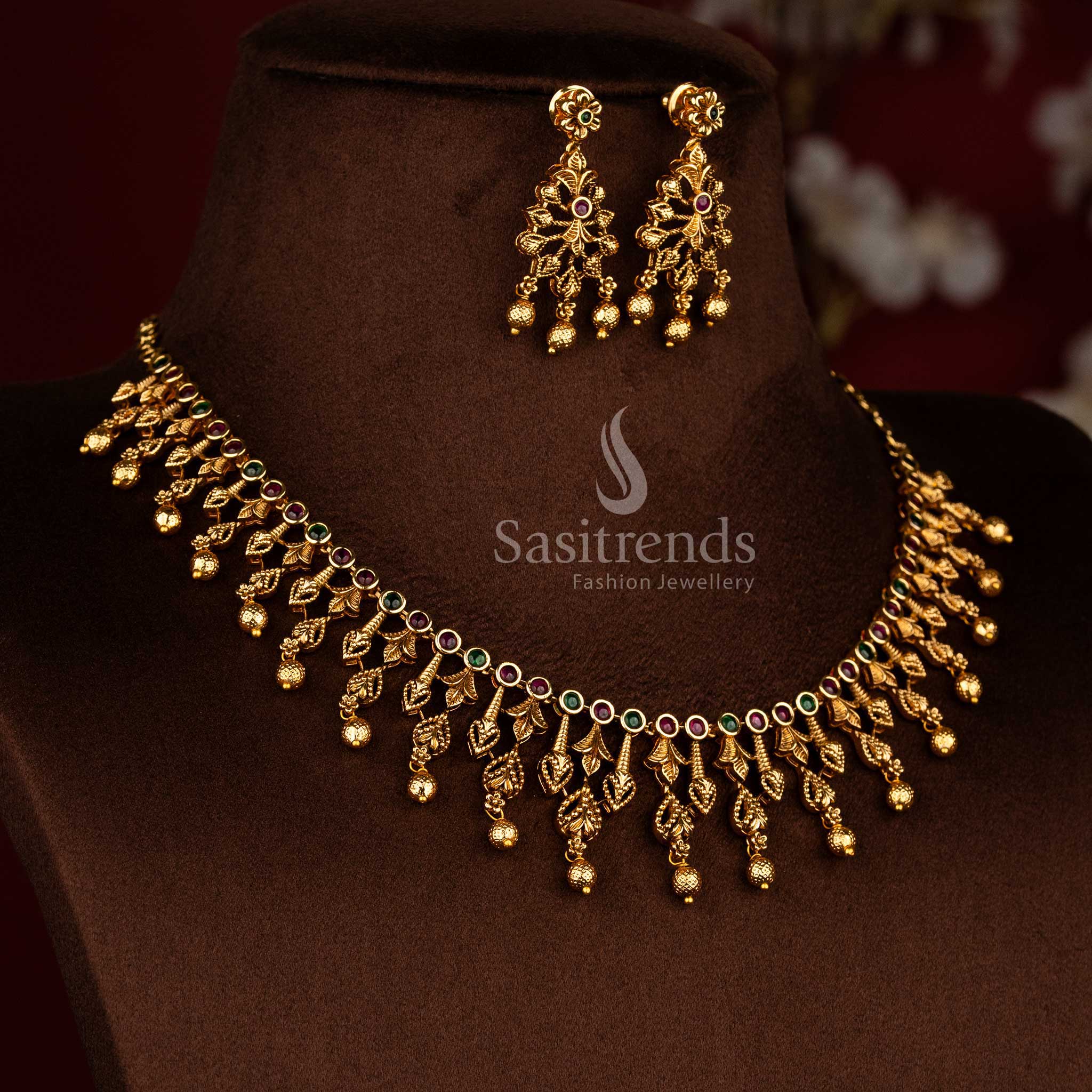 Sasitrends temple jewellery matte gold ruby green AD stone necklace set with structured circular stone neckline and graceful hanging bead elements