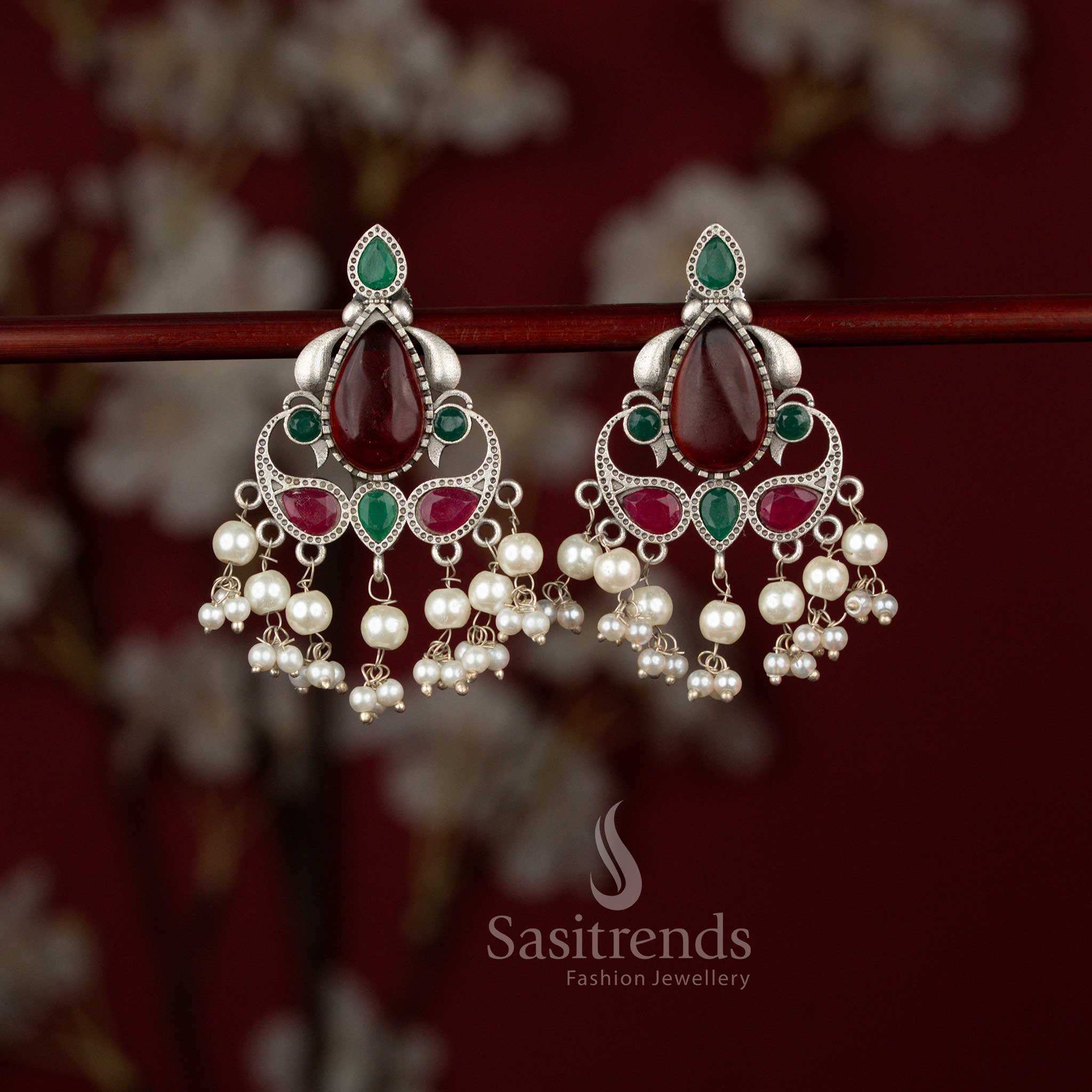 Traditional ruby green peacock motif oxidised silver earrings by Sasitrends showcasing intricate metal artistry, vibrant teardrop stone accents and elegant pearl drops for ethnic celebrations and festive wear.