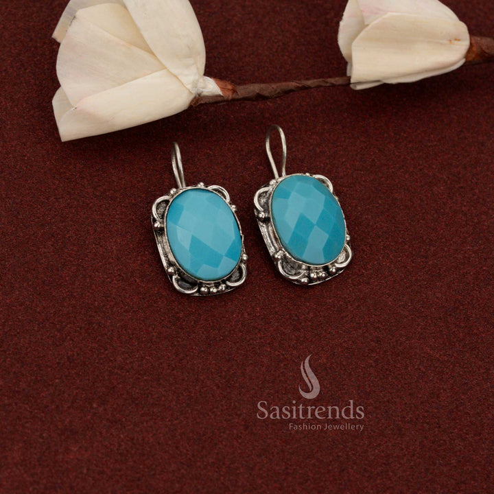 Sasitrends structured oxidised German silver earrings showcasing oval faceted sky blue stone enclosed in a floral border frame