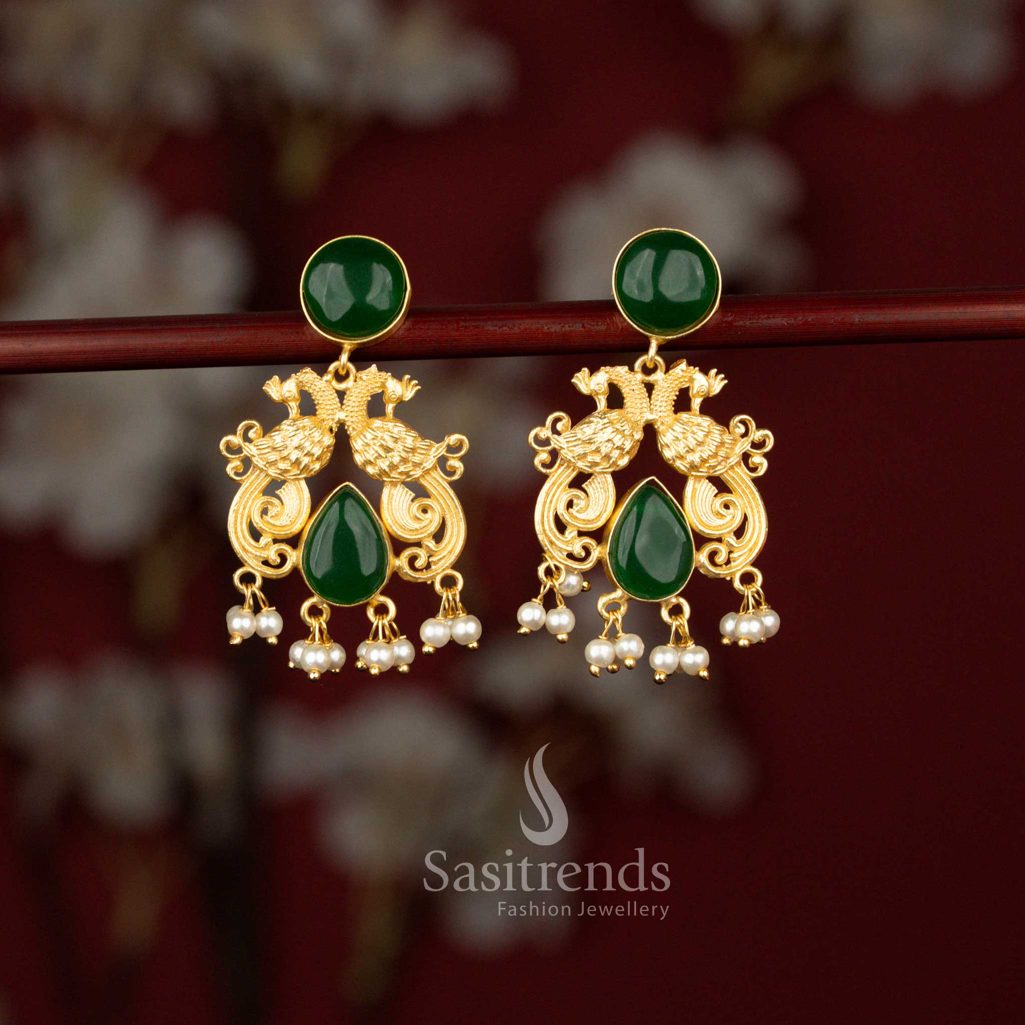 Traditional green 24K gold plated dual peacock earrings from Sasitrends featuring a circular motif, sparkling teardrop stones and graceful pearl drops that enhance sarees and ethnic wear beautifully.