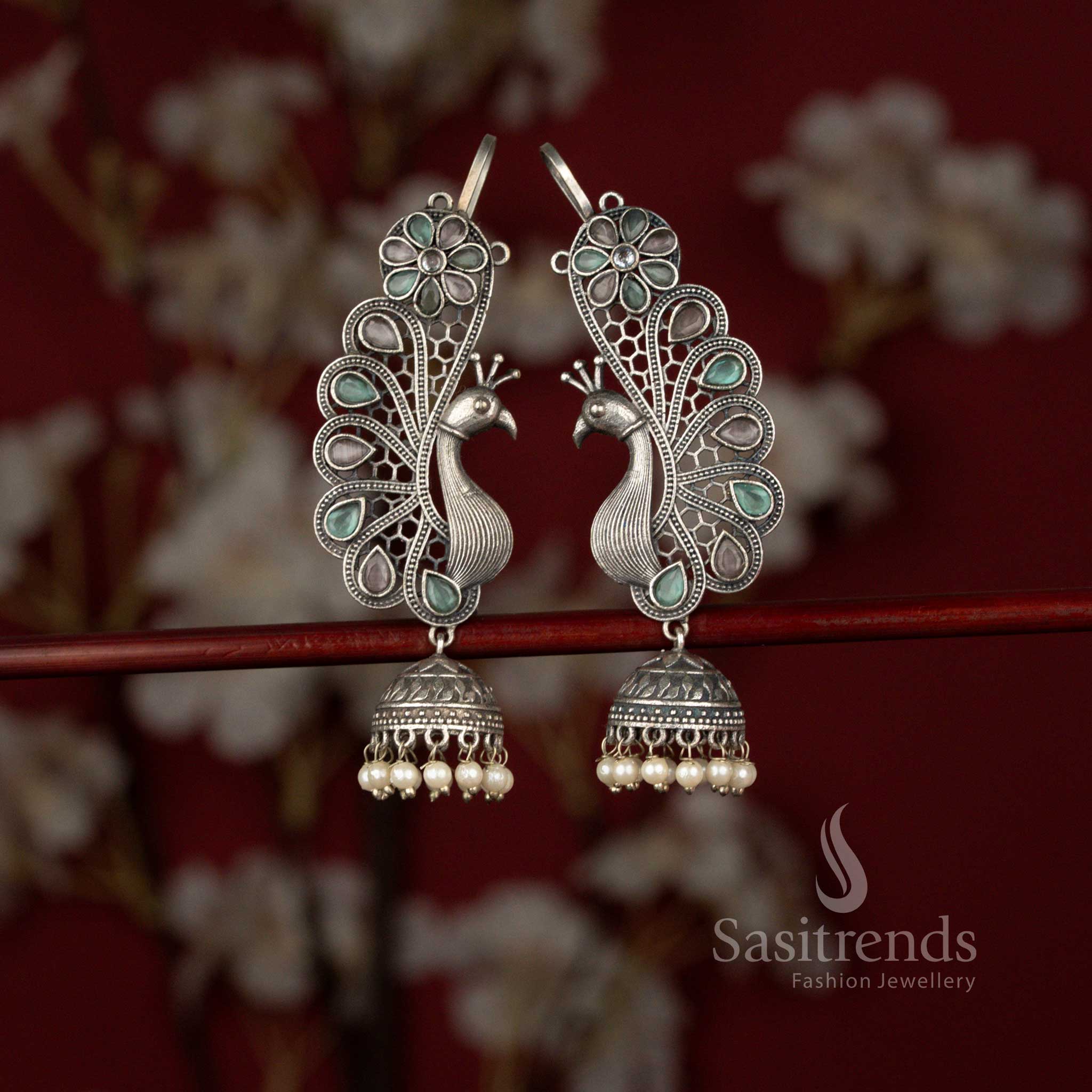Traditional oxidised silver plated peacock floral earcuff earrings from Sasitrends featuring detailed metal carving, elegant teardrop mint pink stone highlights and cascading pearl jhumka drops perfect for sarees and festive gatherings.