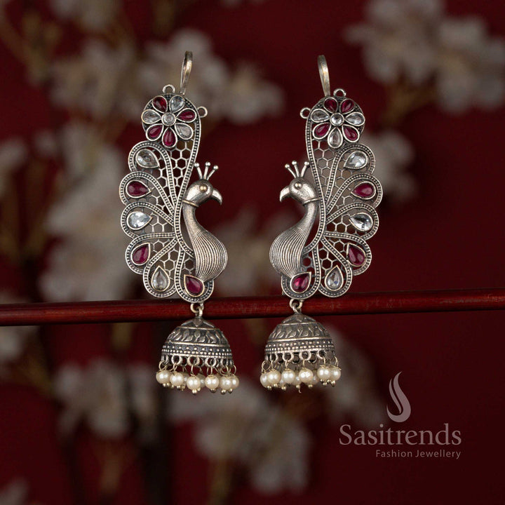Sasitrends white ruby antique finish oxidised silver earcuff earrings showcasing a peacock and floral inspired structure, highlighted with teardrop stones and finished with layered pearl jhumka detailing for traditional styling.