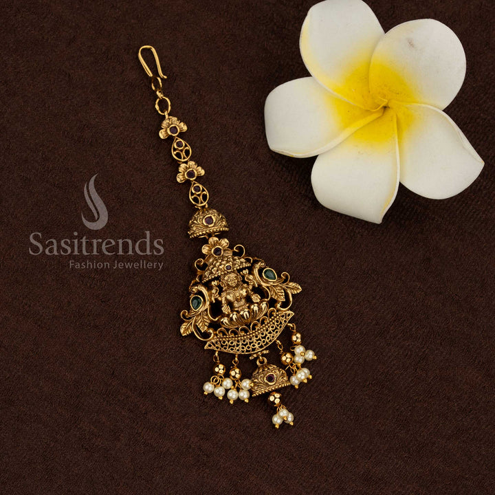 Premium temple matte gold plated Lakshmi maang tikka with intricate filigree work, Kemp stone accents, clustered pearl drops, high quality traditional jewellery for bridal and wedding wear - Sasitrends
